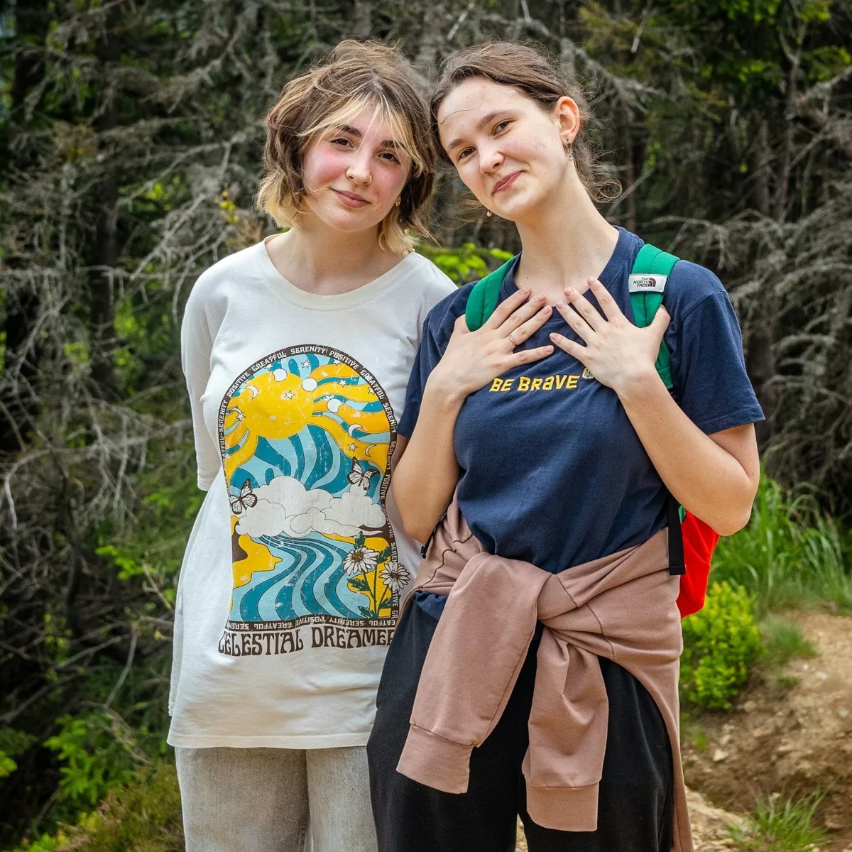 Two young women posing together in a forest